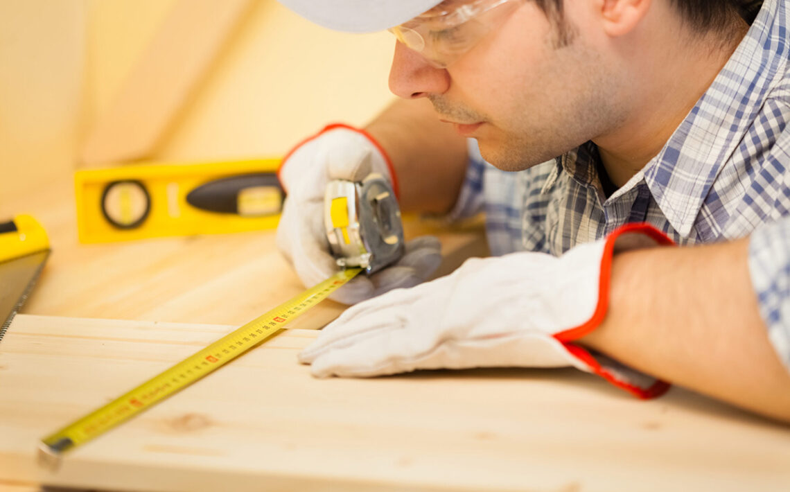 Worker measuring wood board